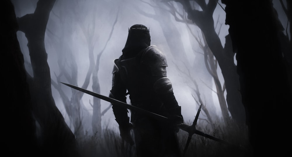 a man in a hooded suit holding a sword in a dark forest