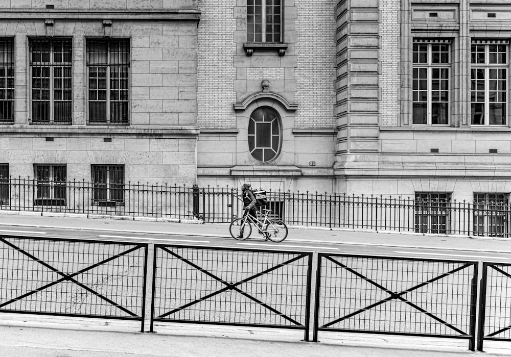 a man riding a bike down a street next to a tall building