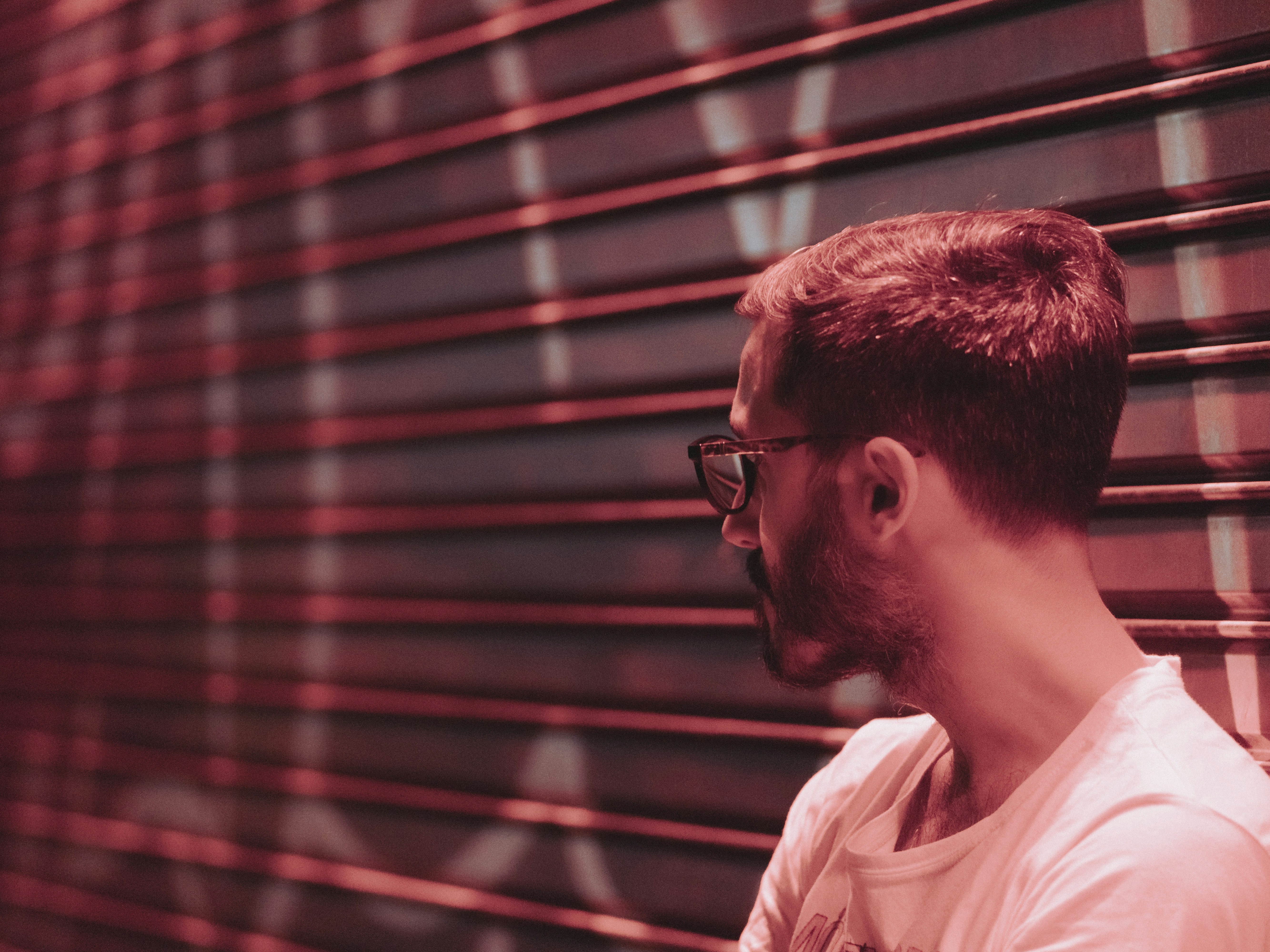 a man with glasses standing in front of a wall