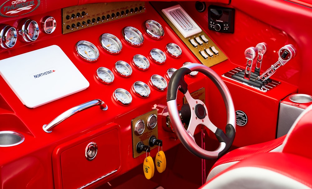 the interior of a red car with a steering wheel and gauges