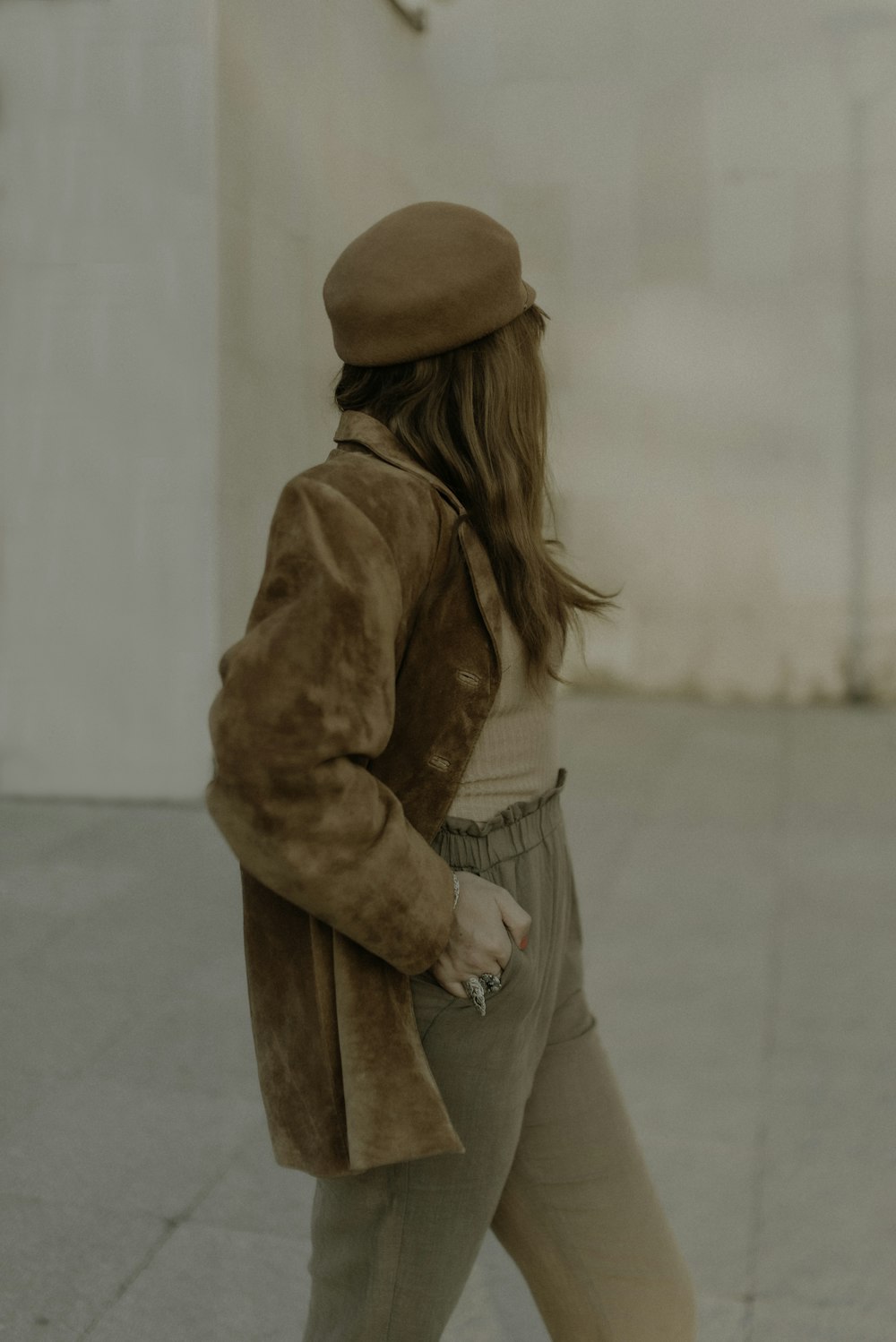 a woman walking down a sidewalk with a hat on