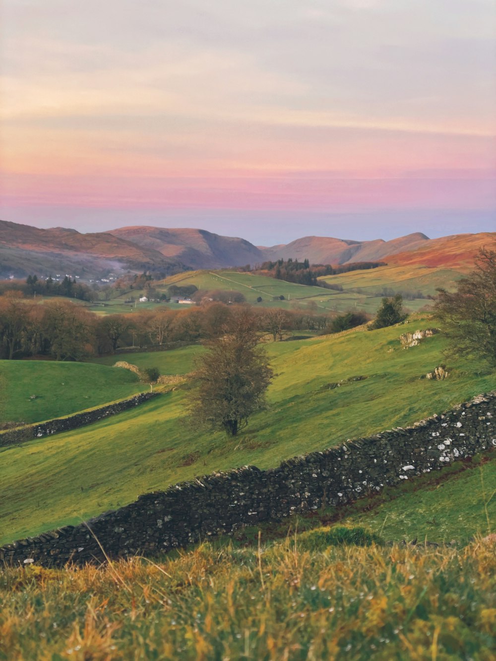 a grassy hill with a stone wall in the foreground