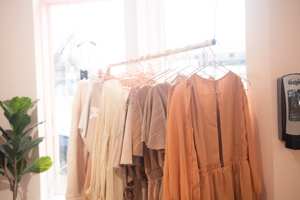 a rack of clothes hanging on a wall next to a window