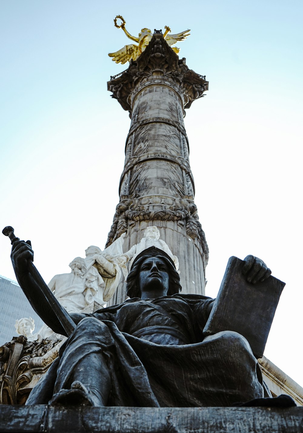 une statue d’un homme assis devant une haute tour