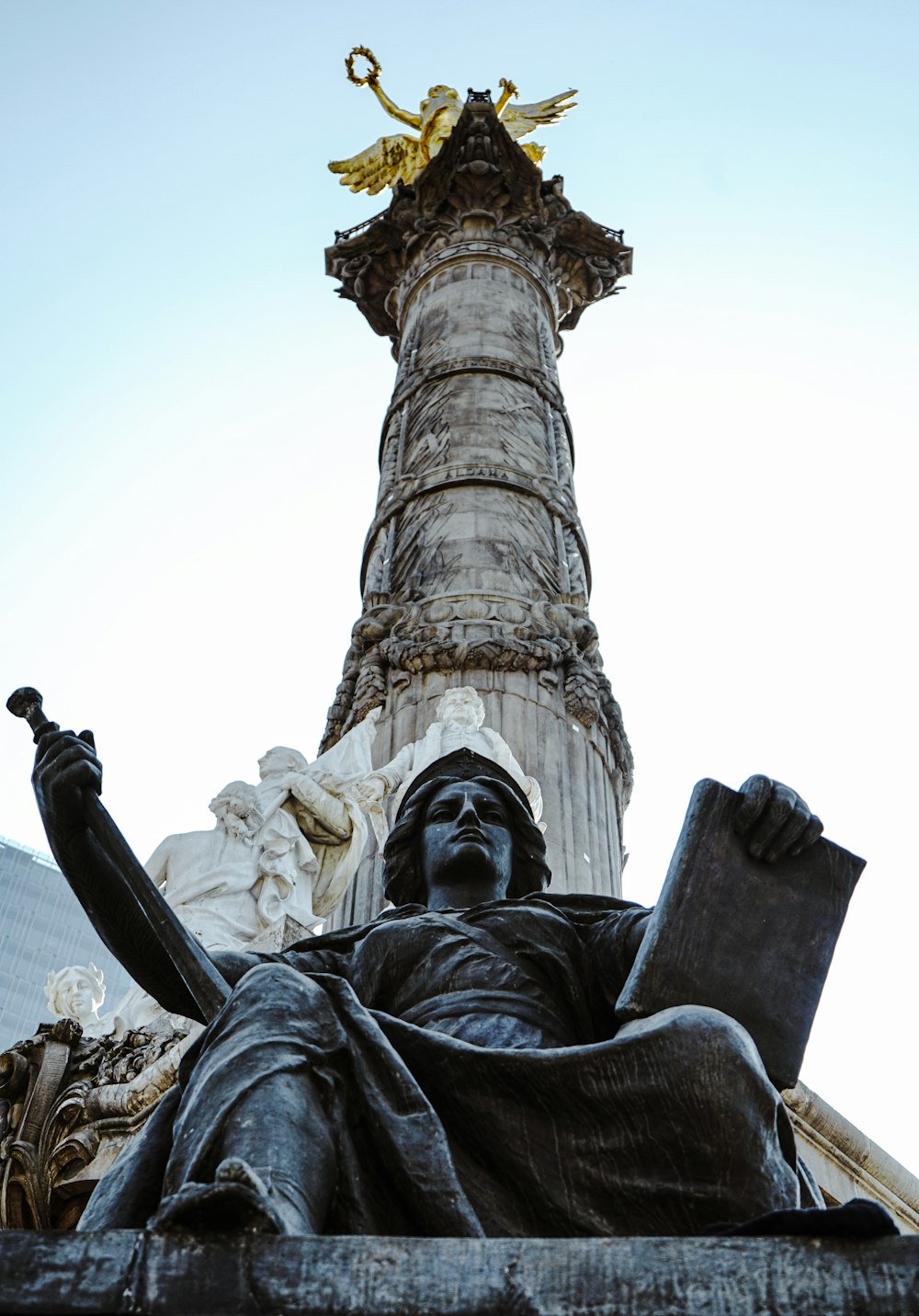a statue of a man sitting in front of a tall tower