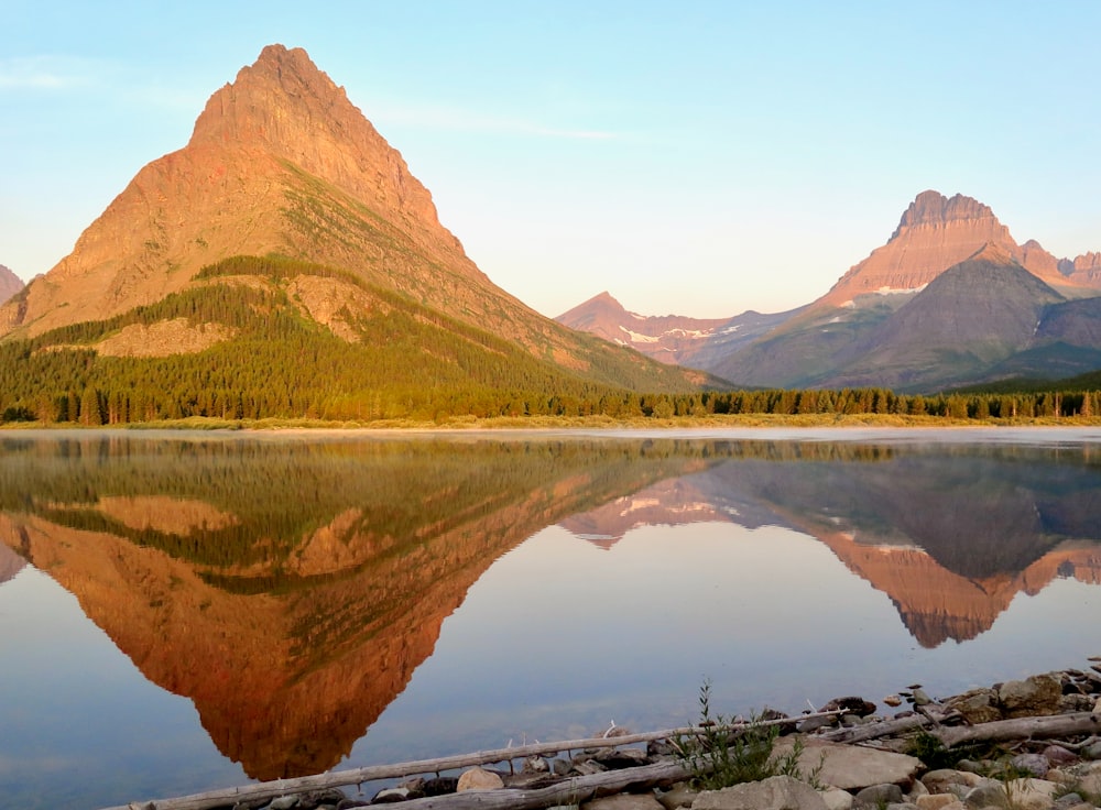 the mountains are reflected in the still water of the lake