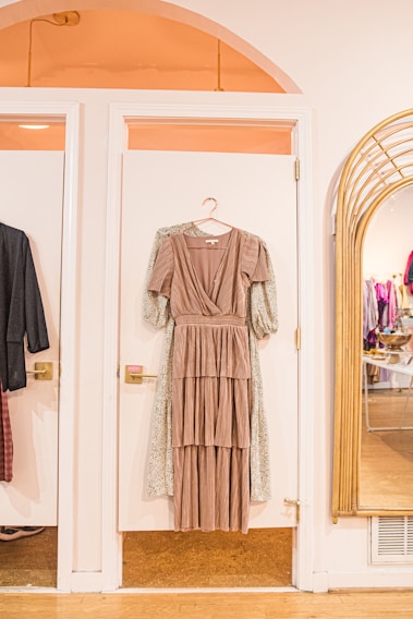 A vibrant display of women's dresses hanging in a cozy boutique setting with warm lighting.