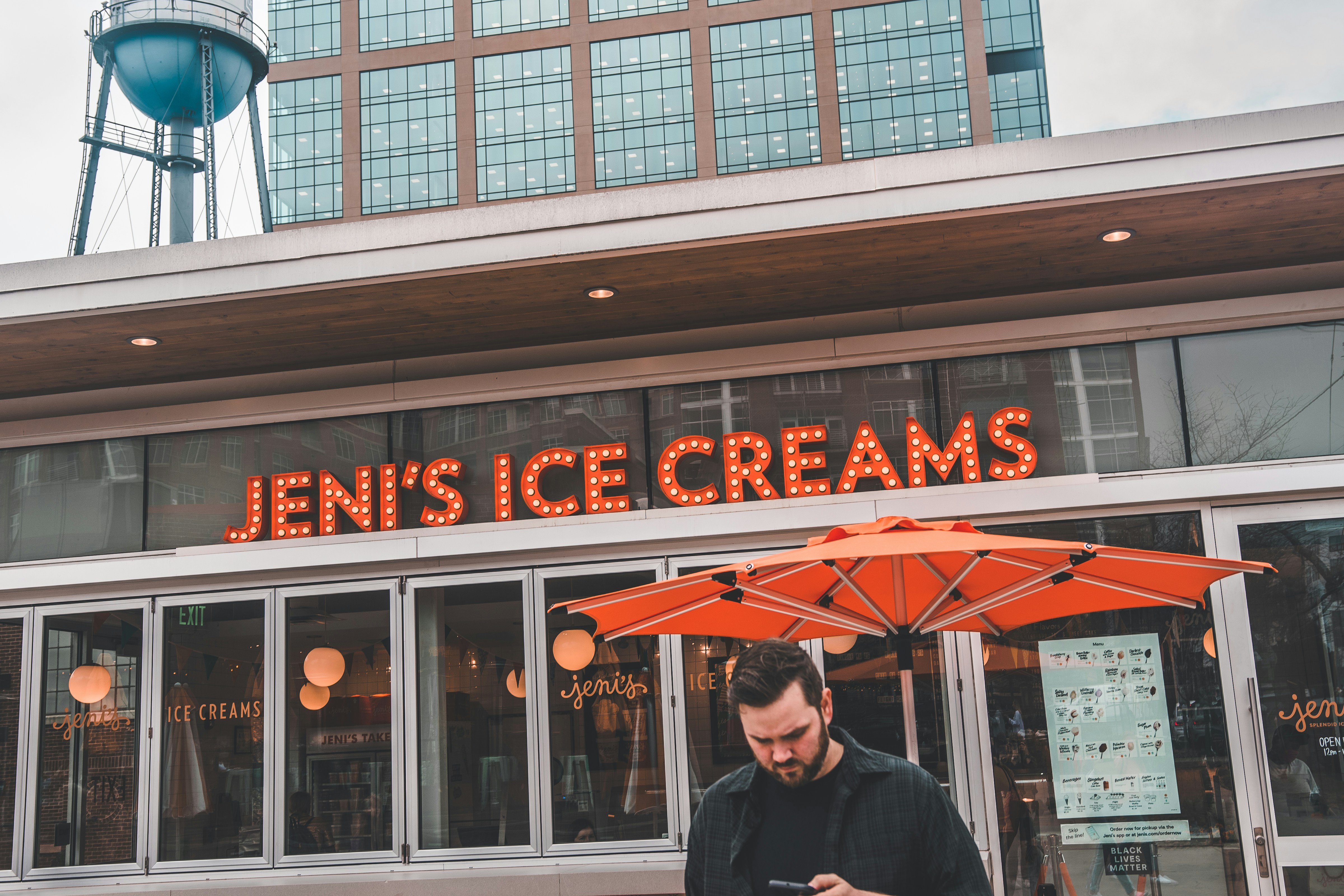 a man standing in front of a store looking at his cell phone