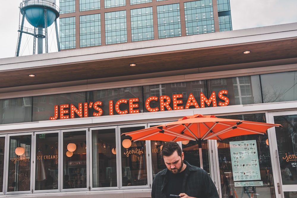 a man standing in front of a store looking at his cell phone