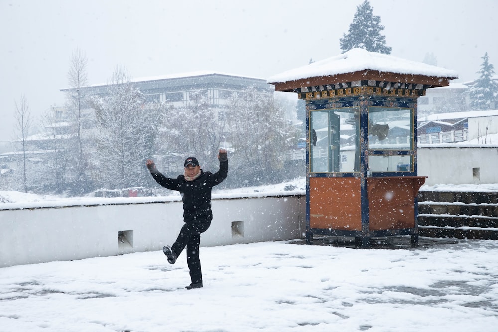 a man standing in the snow with his arms in the air