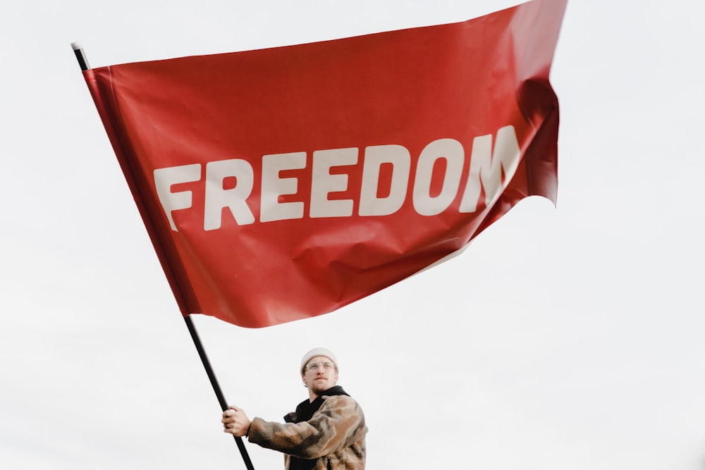 Un homme tenant un drapeau rouge avec le mot liberté dessus