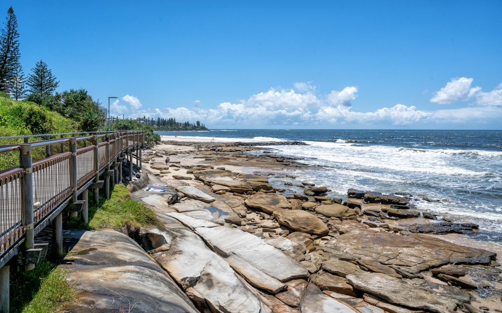 a wooden walkway next to the ocean on a sunny day