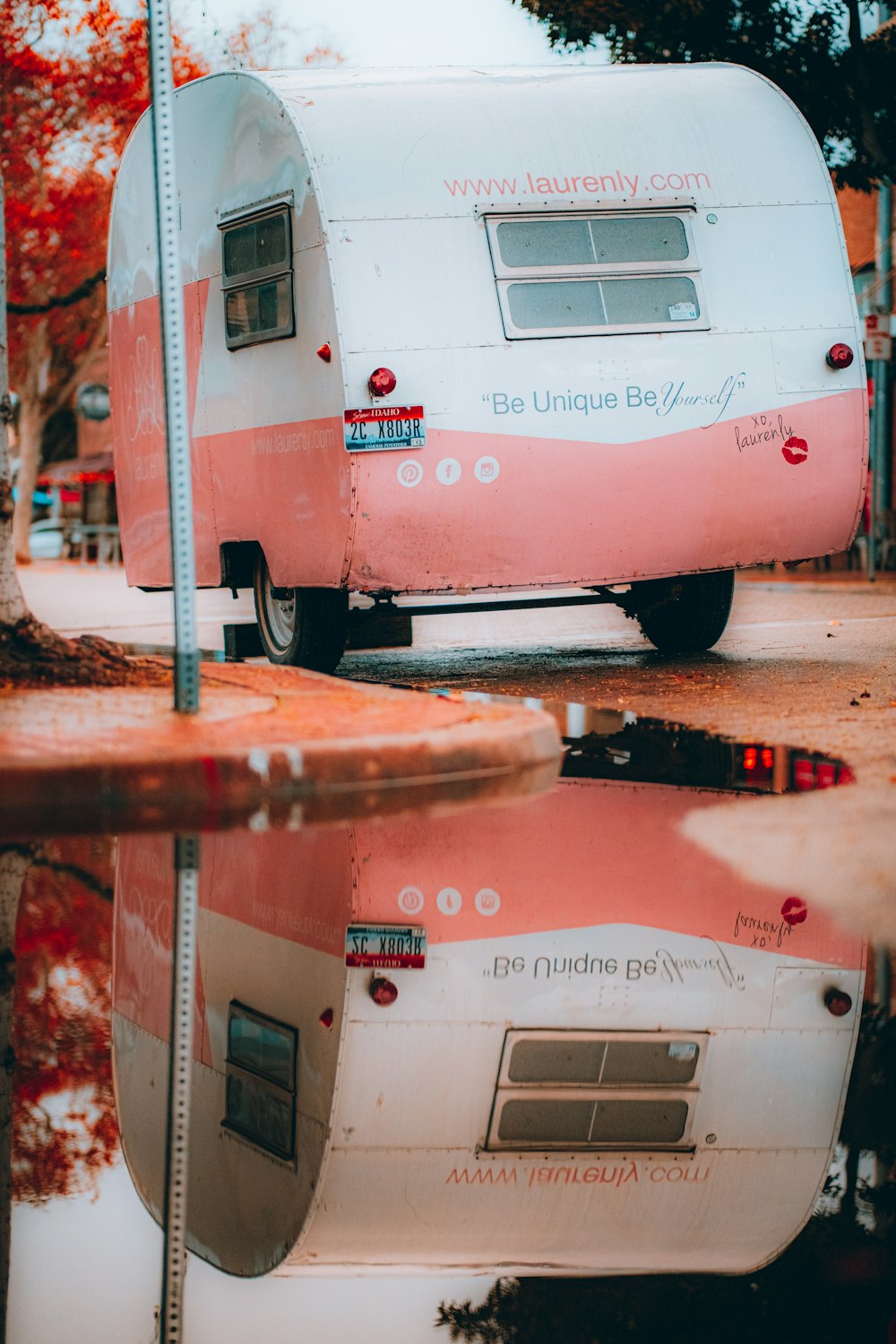 a pink and white trailer parked on the side of a road
