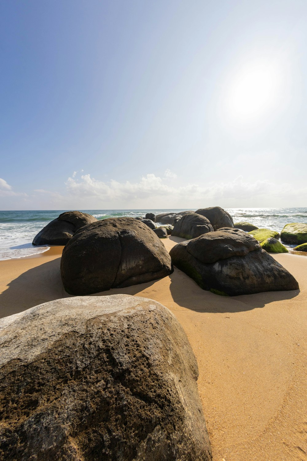a sandy beach with large rocks in the sand