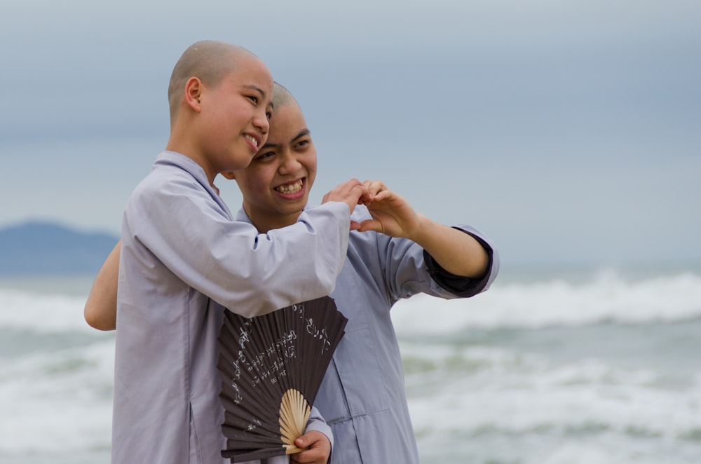 a couple of men standing next to each other near the ocean