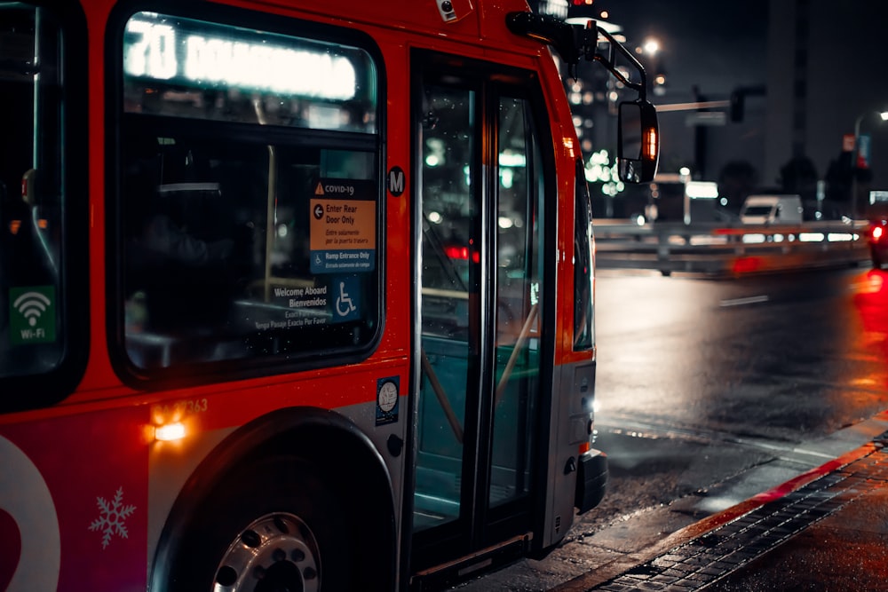 a red bus driving down a street at night