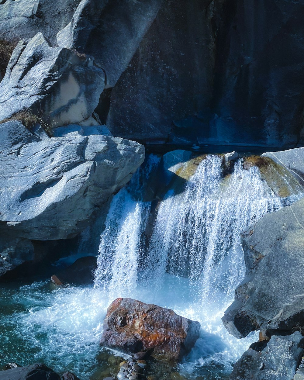 a waterfall with a large rock in the middle of it