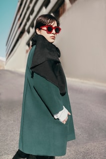 A street-style portrait of someone wearing a bold patterned coat with vintage sunglasses.