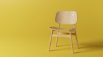 Modern wooden chair with clean lines set against a minimalist backdrop