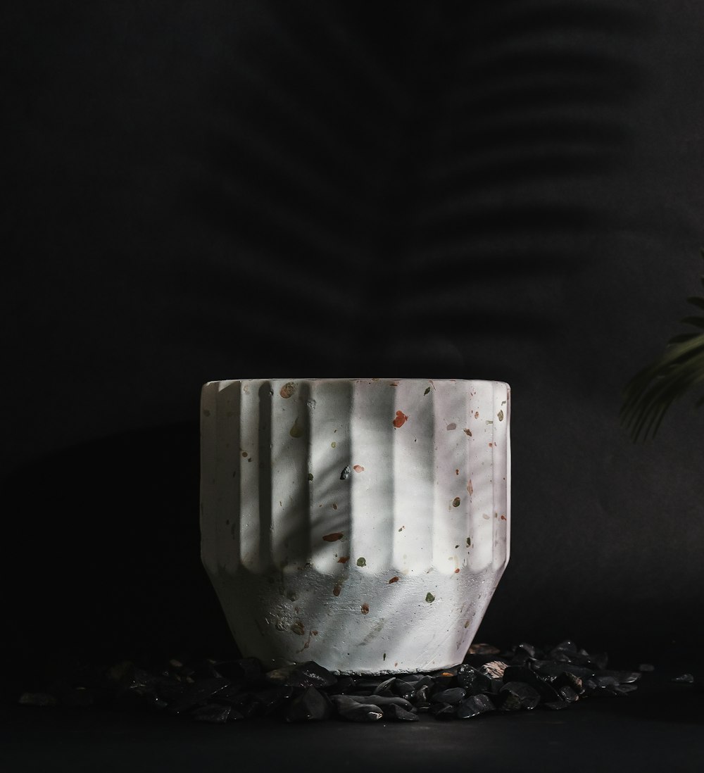 a white vase sitting on top of a table next to a plant