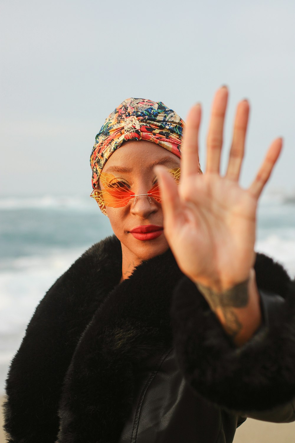 a woman in a black jacket and a scarf on a beach