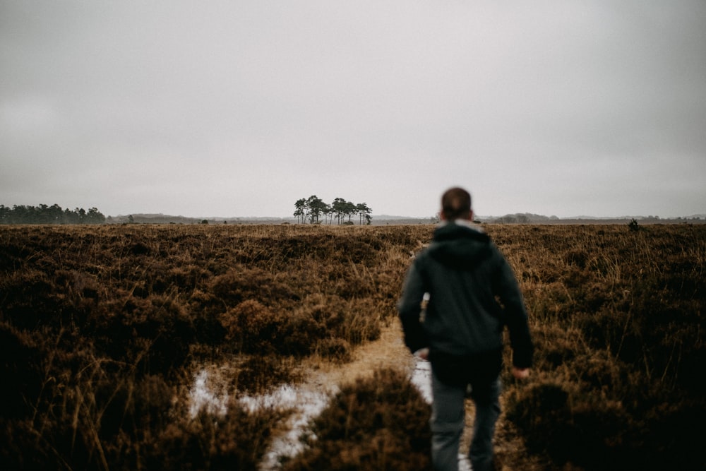 a person walking in a field with trees in the background