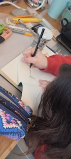 Smiling student writing in a notebook surrounded by school supplies