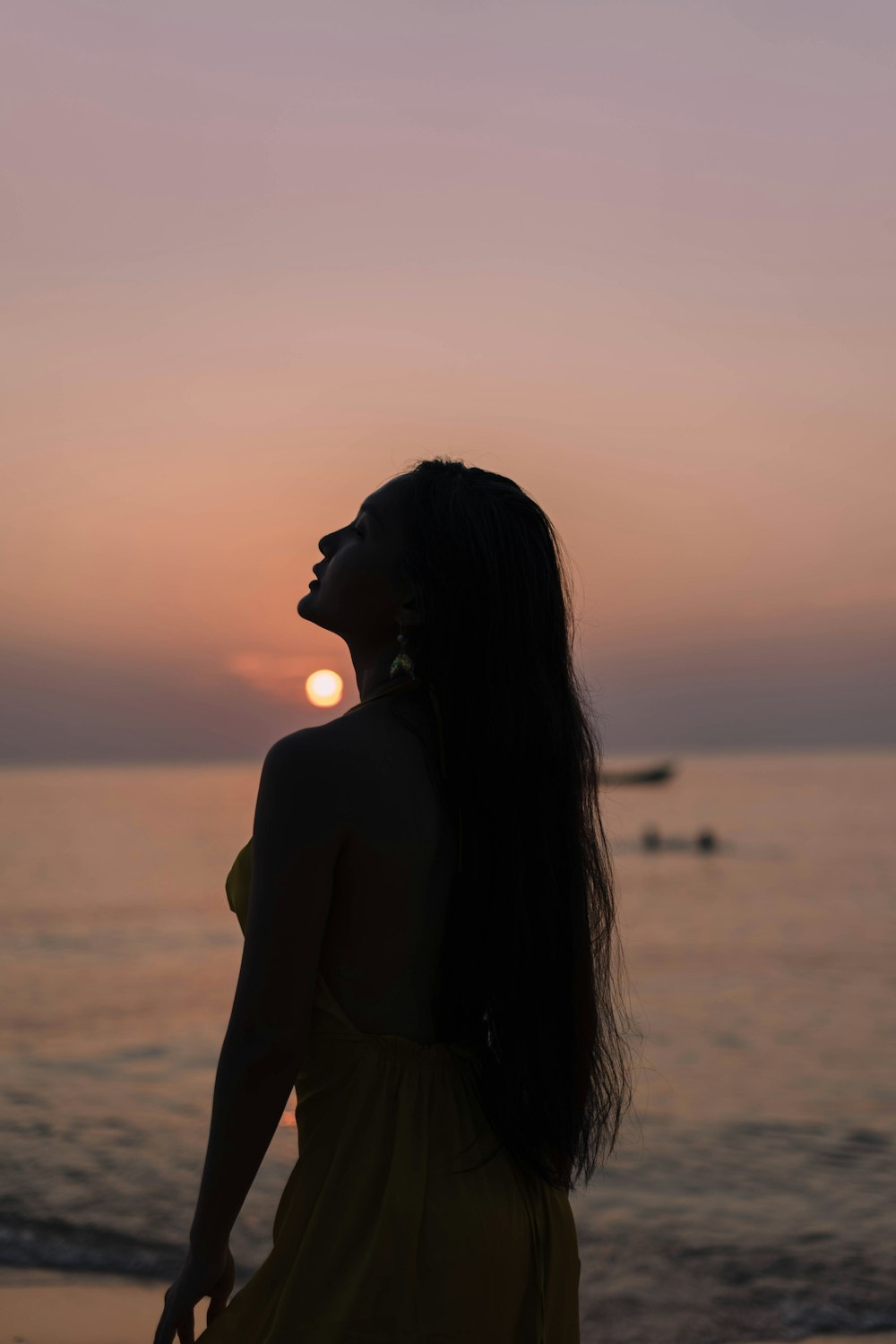 a woman standing on a beach at sunset