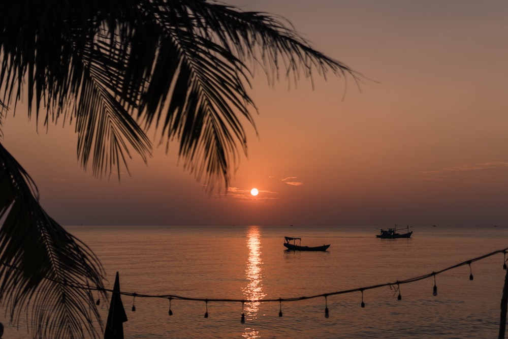 a sunset over a body of water with a boat in the distance