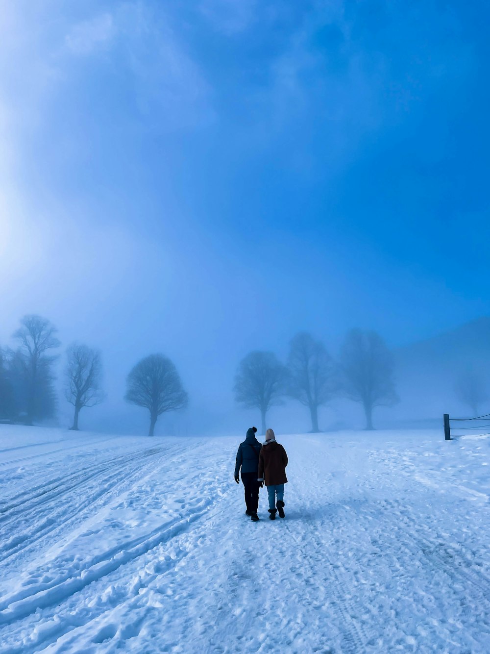 Ein paar Leute gehen über ein schneebedecktes Feld