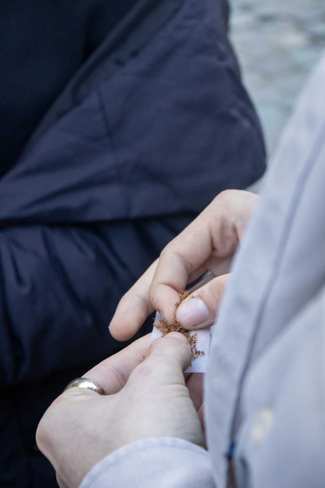 Hände drehen mit losem Tabak eine Zigarette