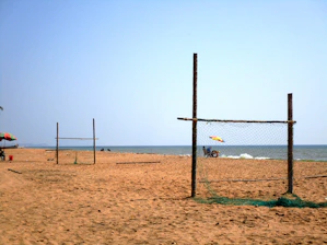 Outdoor beach soccer field under a clear sky with players ready to start.
