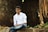 a man sitting on a rock in front of a building