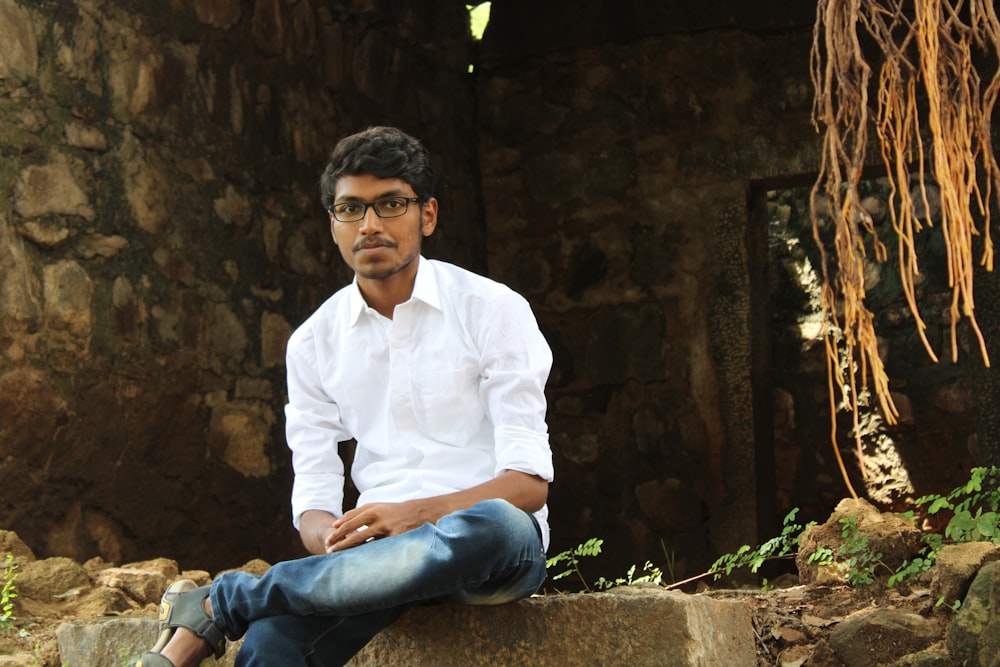 a man sitting on a rock in front of a building