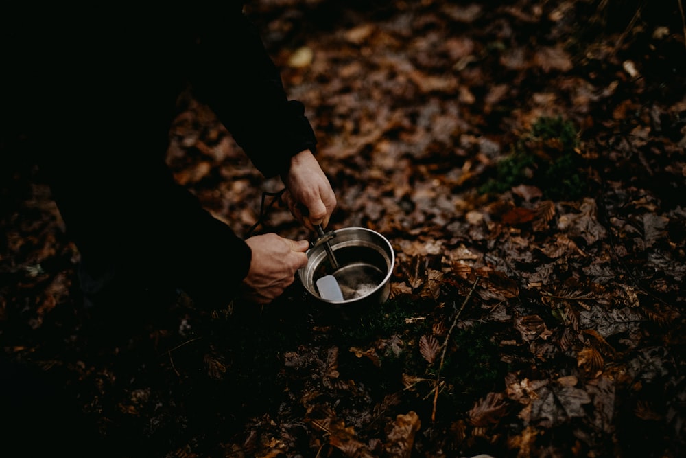 a person holding a metal bowl in the woods