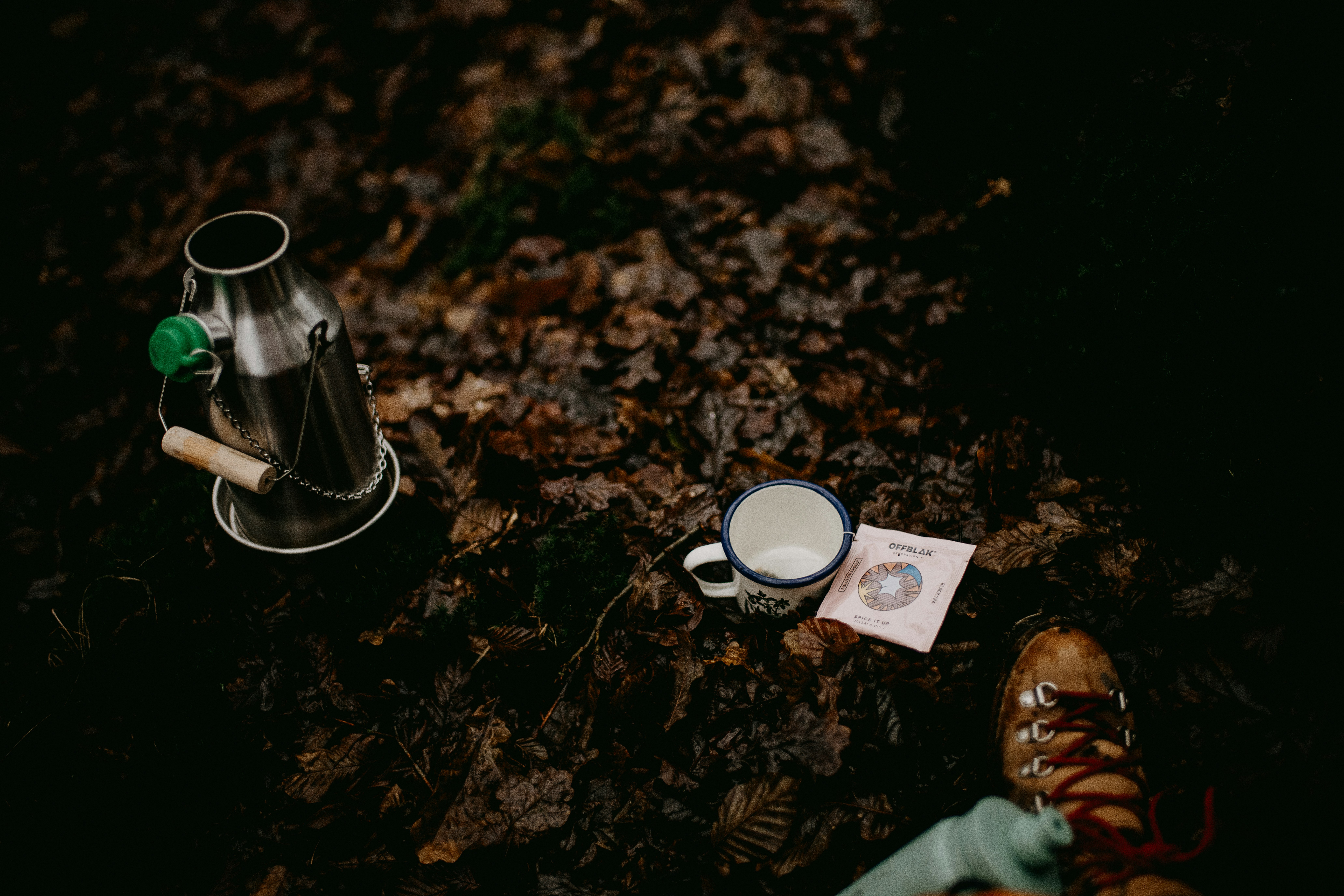 a cup of coffee sitting on top of a leaf covered ground