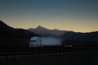 a white truck driving down a road next to mountains