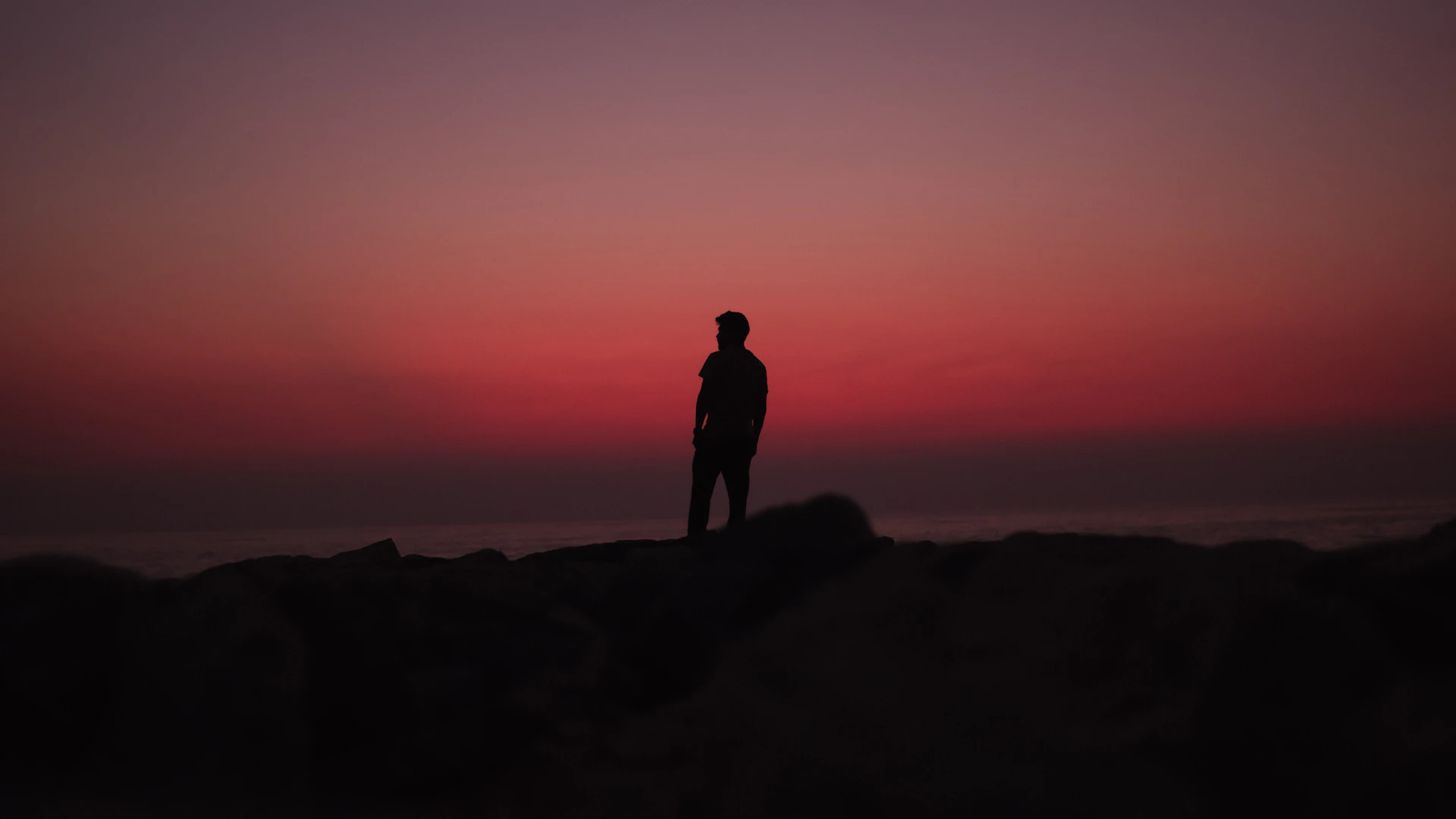 a man standing on top of a rocky beach next to the ocean