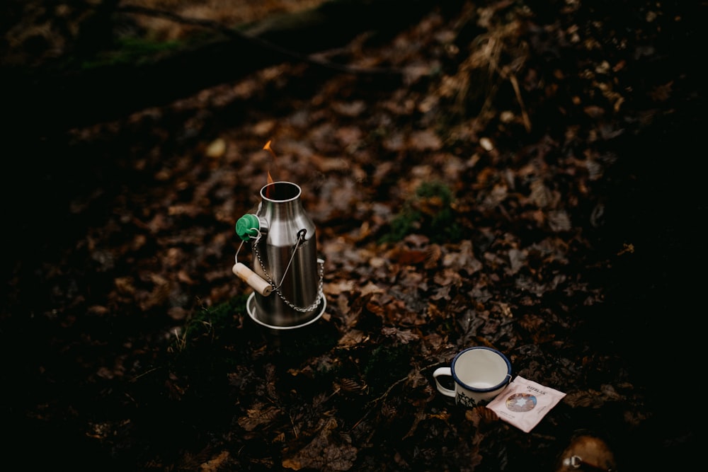 a cup of coffee sitting on top of a forest floor