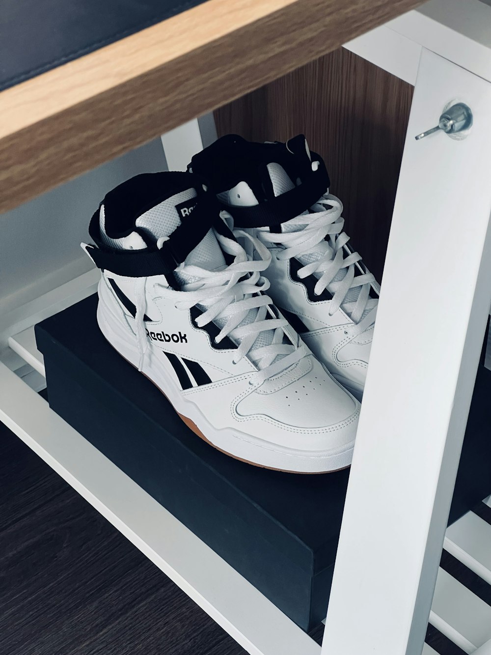 a pair of white shoes sitting on top of a shelf