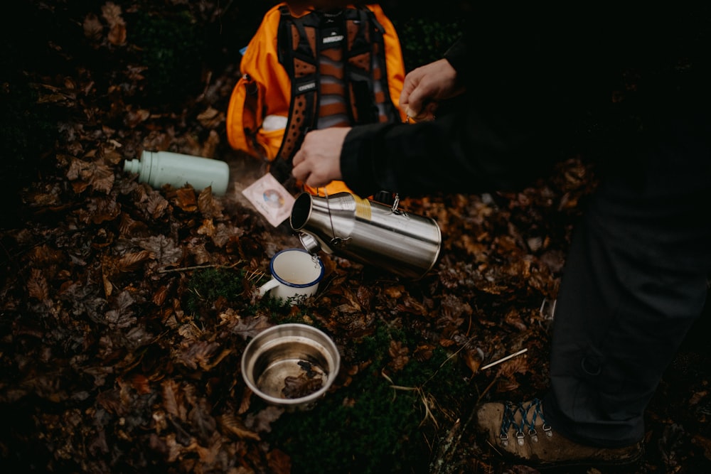 a person pouring water into a cup on the ground