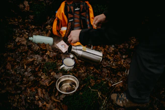 a person pouring water into a cup on the ground