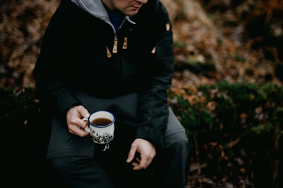 a man sitting on a bench holding a cup of coffee