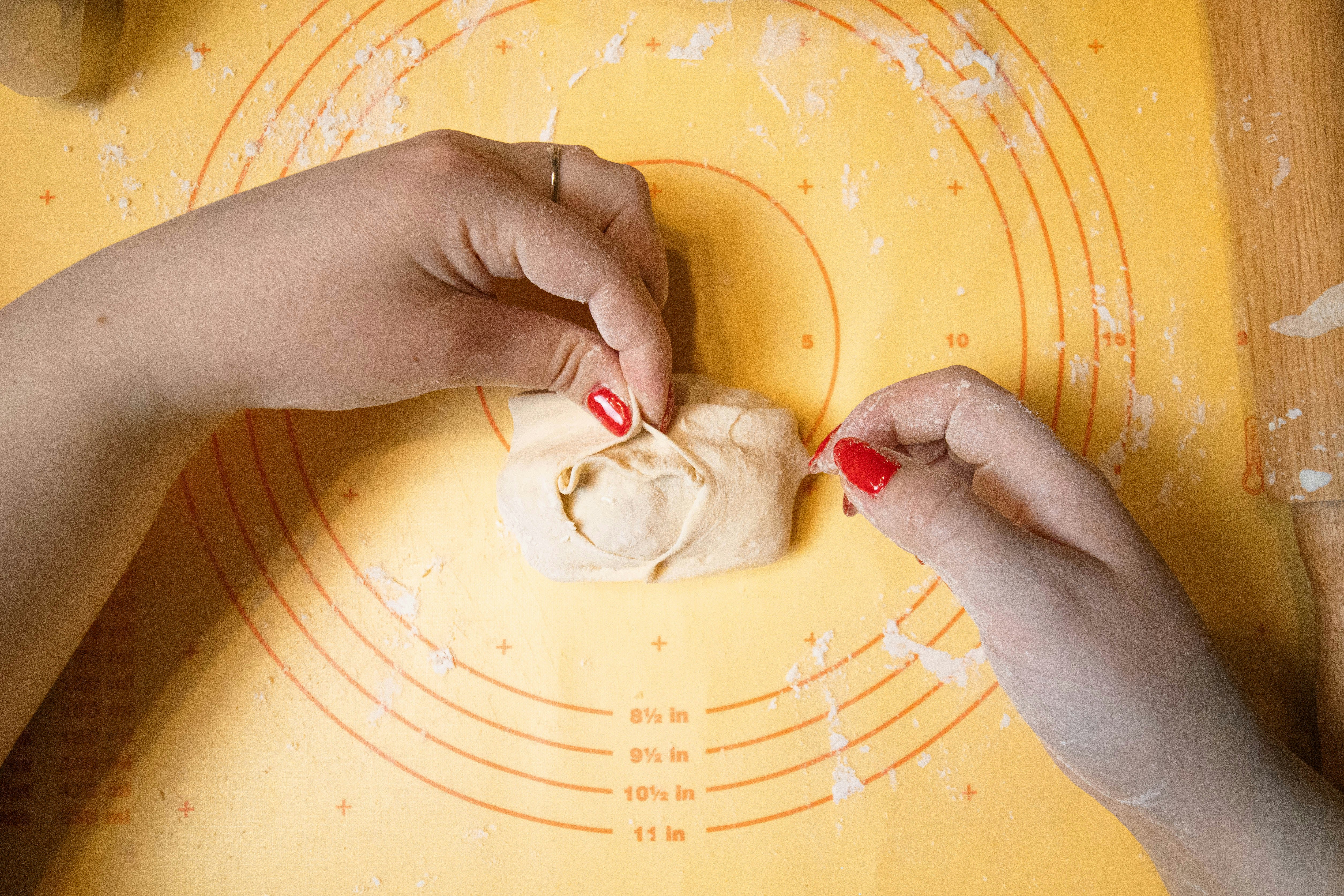 hands pleating and folding a dumpling on a work surface