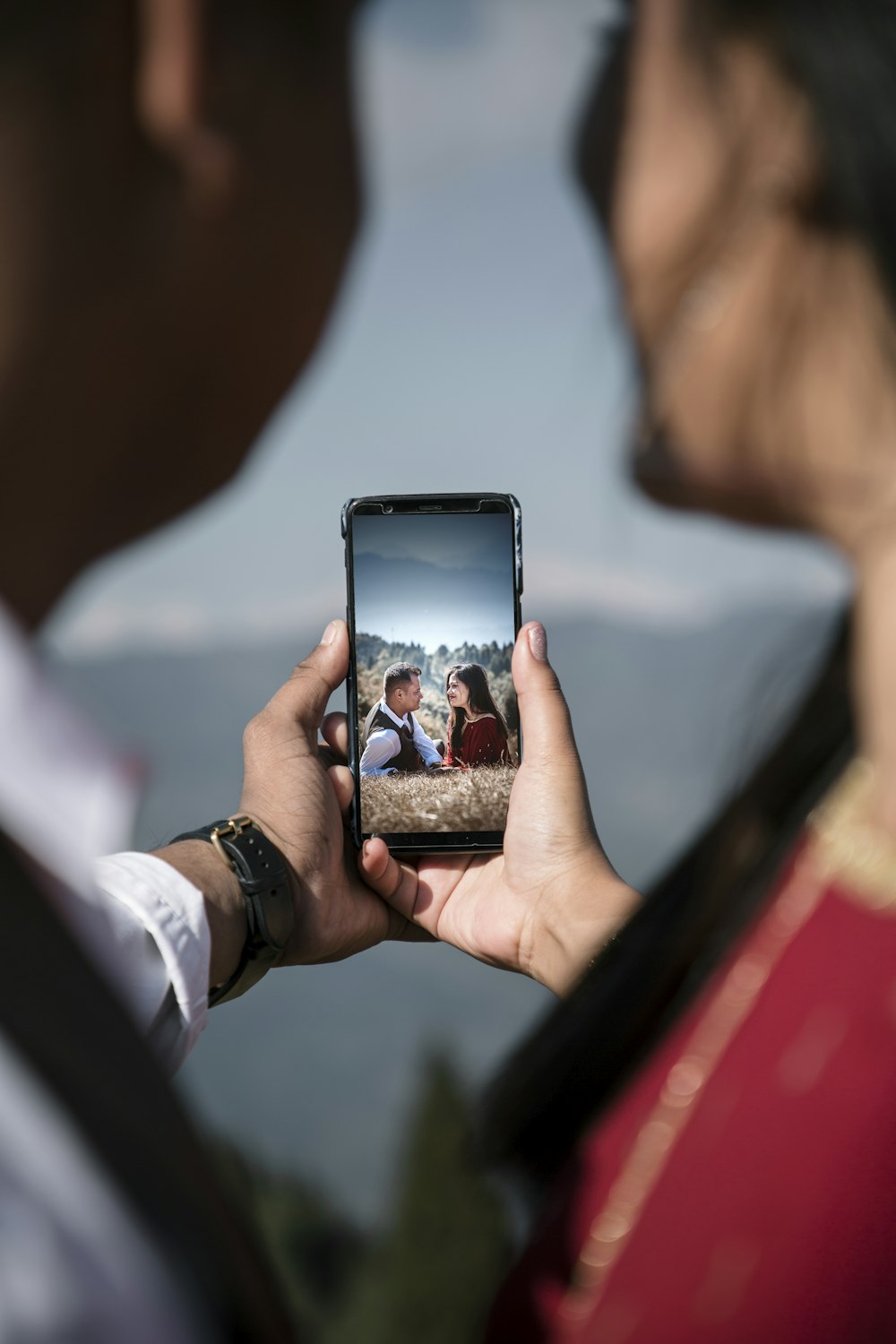 a man taking a picture of a woman holding a cell phone