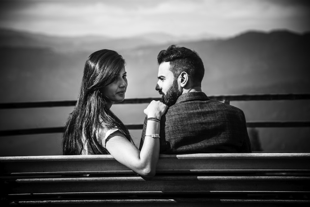 a black and white photo of a couple sitting on a bench