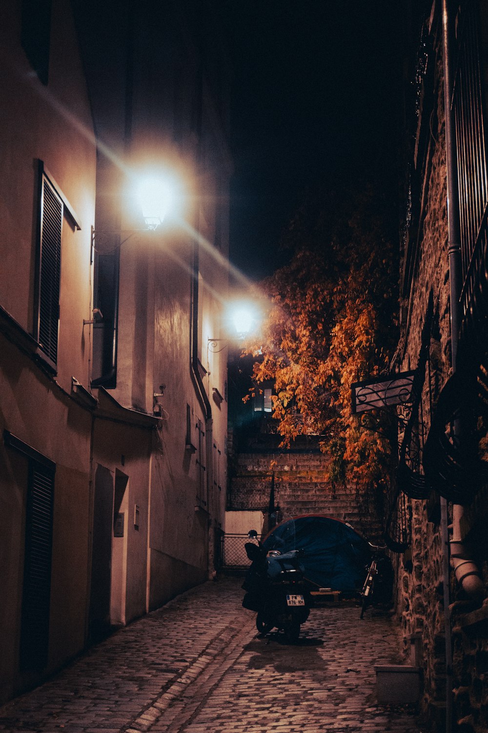 a motorcycle parked on a cobblestone street at night