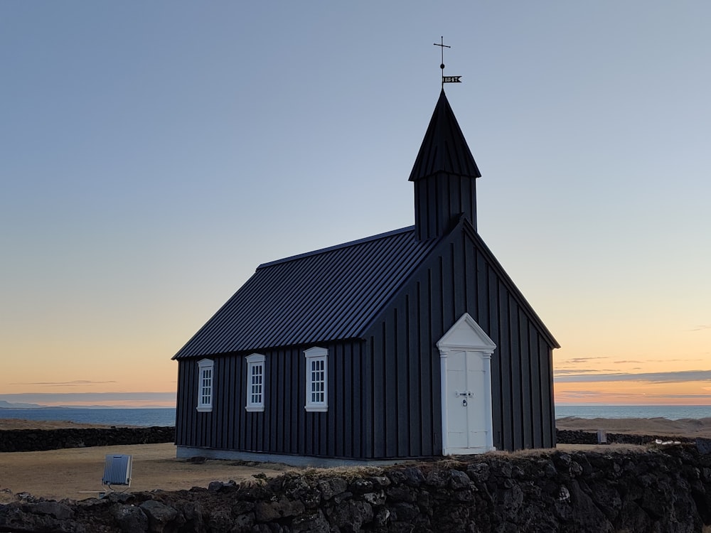 a small black church with a steeple and a cross on top