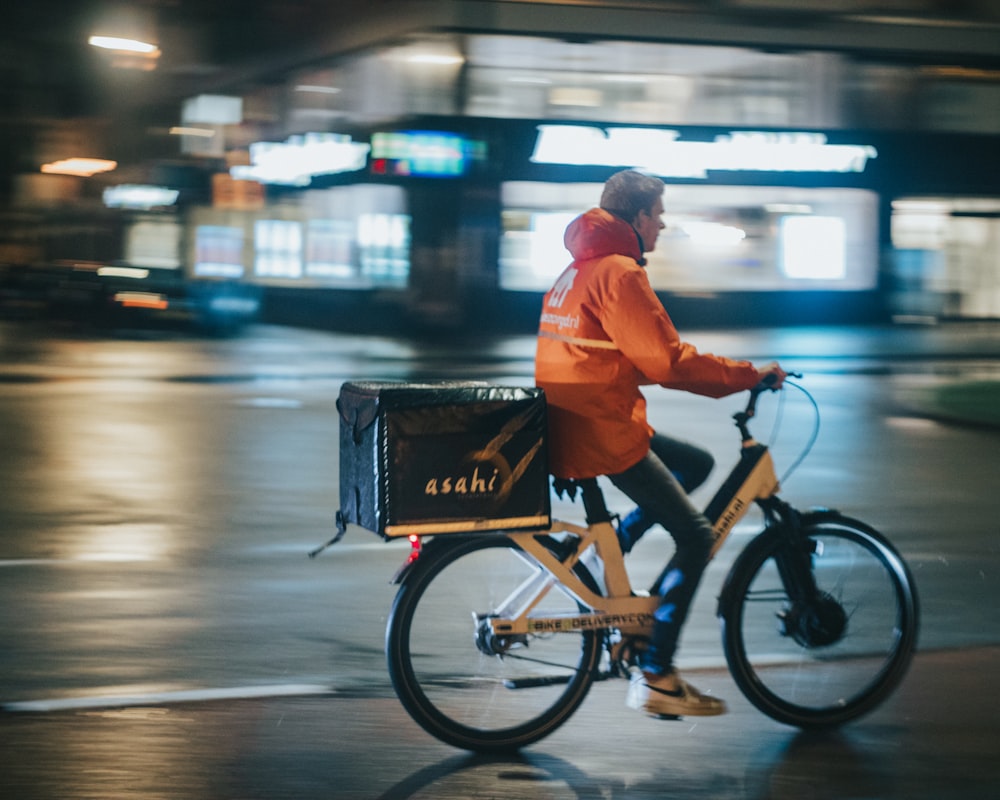 um homem andando de bicicleta por uma rua à noite