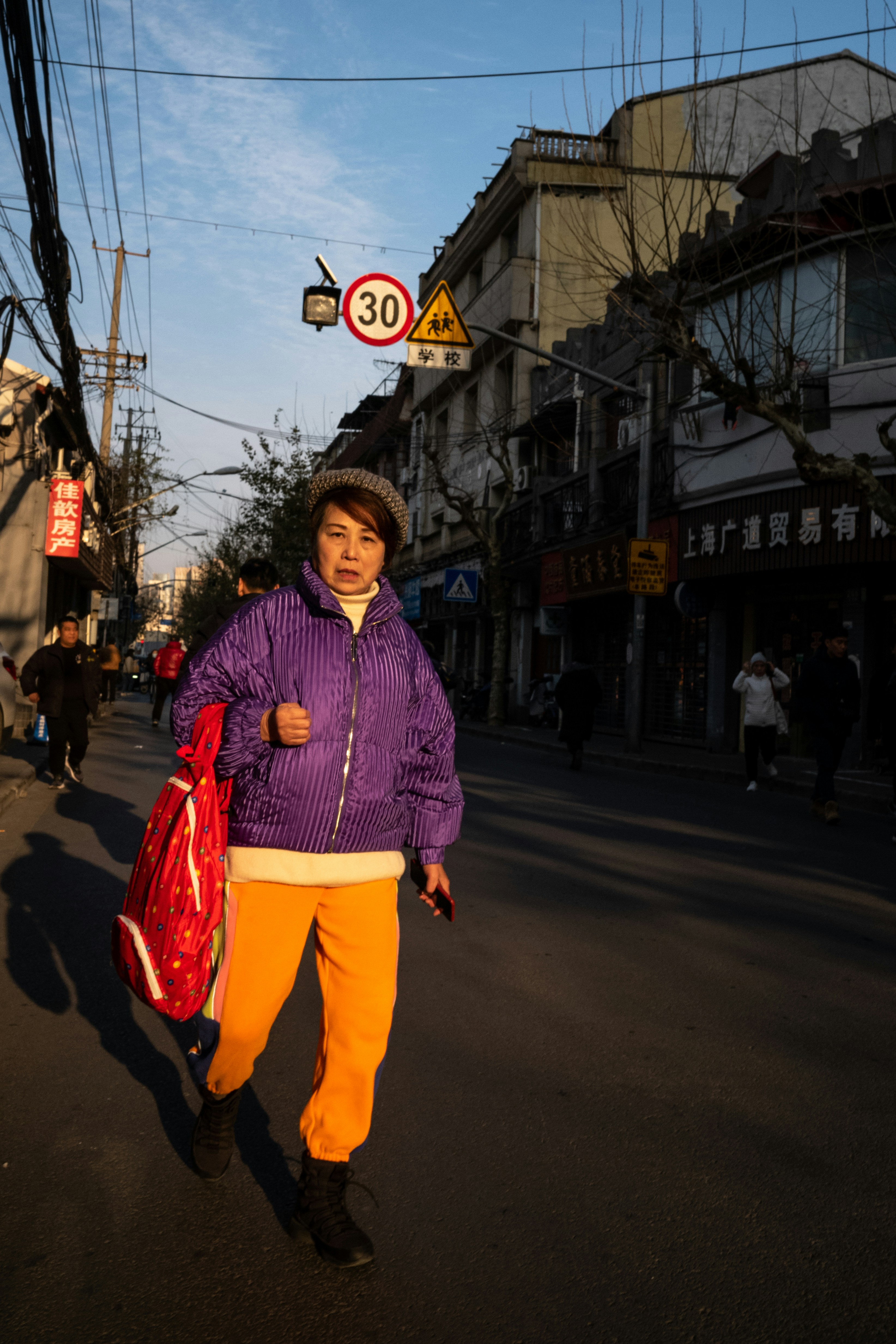 a woman in a purple jacket is walking down the street
